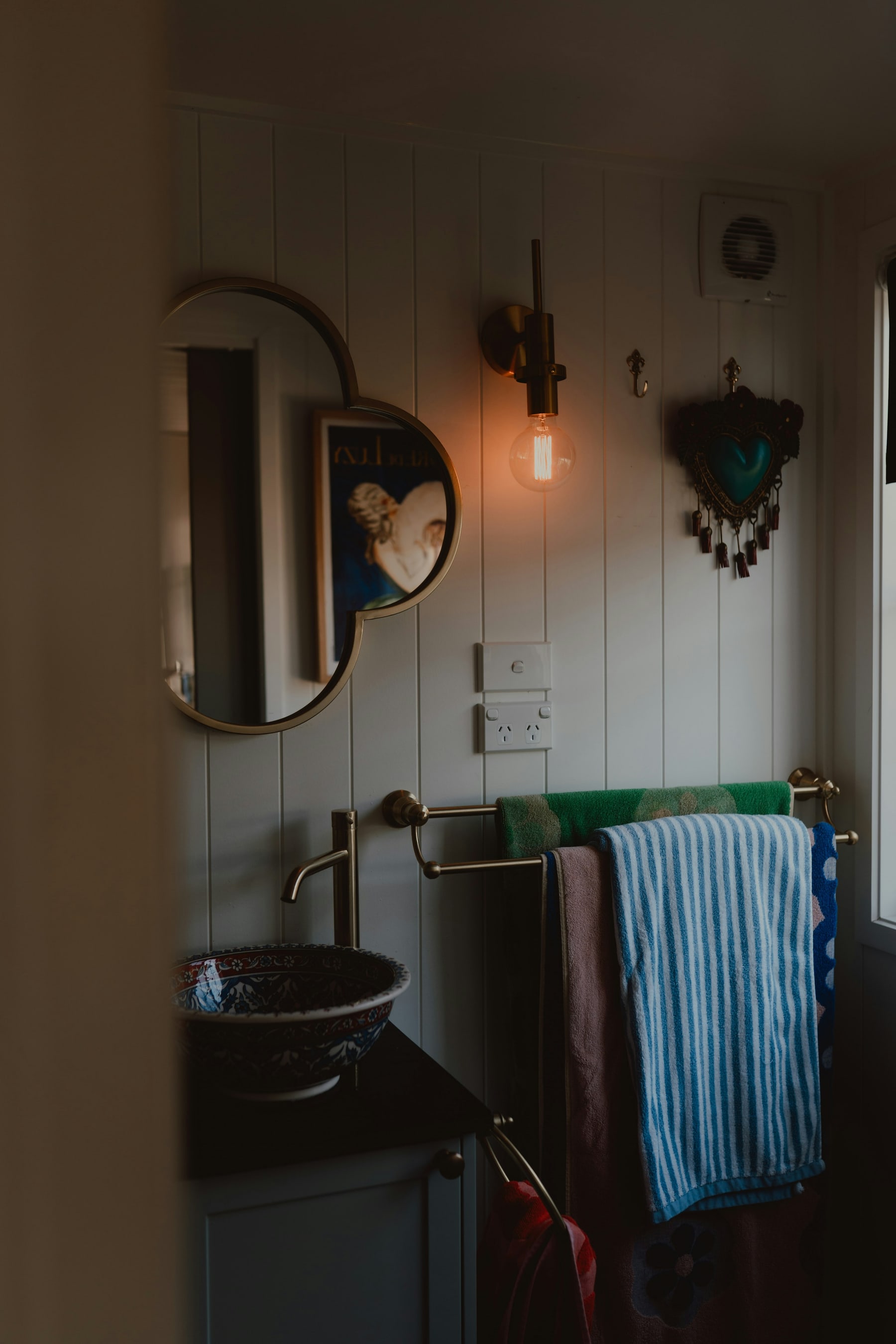 Bathroom mirror and sink with warm light, fresh towels, and natural texture